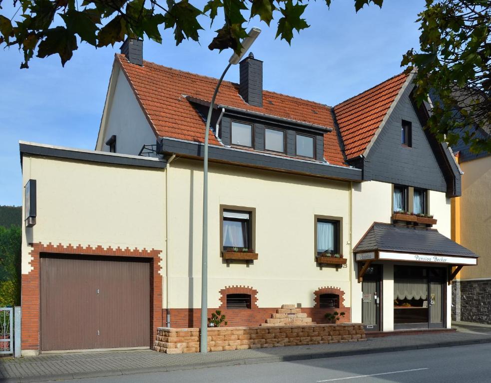 阿恩斯贝格贝克尔膳食公寓的一间白色的房子,有棕色的屋顶和一个车库