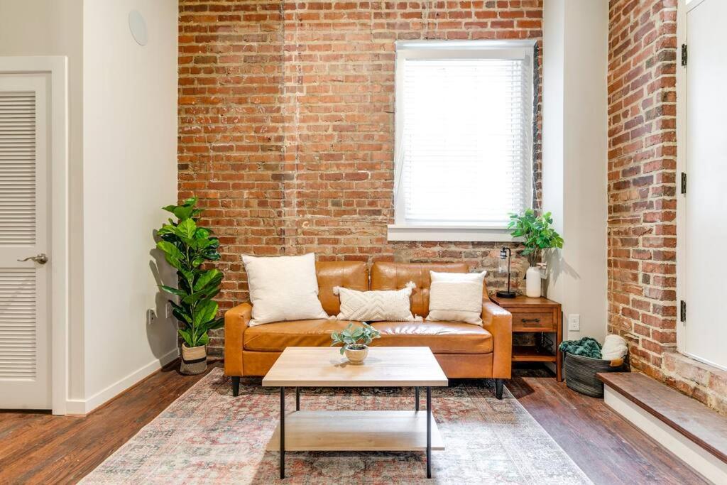 里士满Cozy Chic Retreat in the Heart of RVA的客厅设有棕色的沙发和砖墙