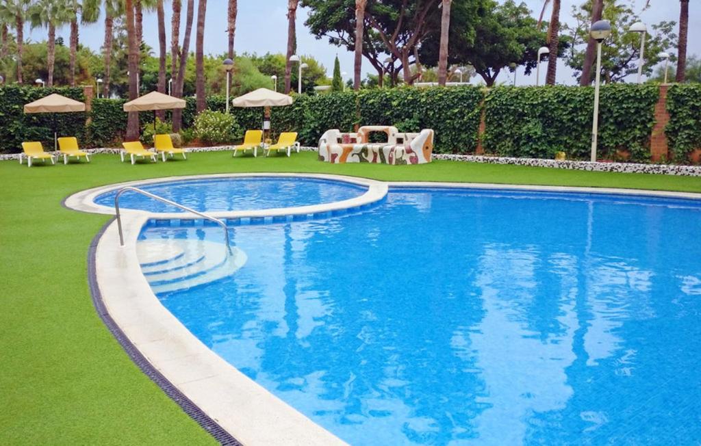 奥罗佩萨德尔马Apartamento de 3 dormitorios, 1º línea de playa en Marina d´Or的度假村内带椅子和遮阳伞的游泳池