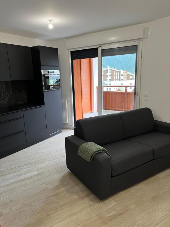 欧龙Superbe studio a Auron avec terrasse plein sud的客厅配有黑色沙发和电视