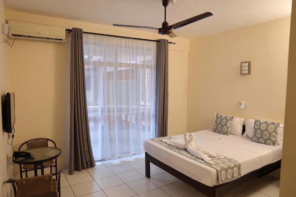 蒙巴萨Merry Villa Hotel & Apartments的一间卧室设有一张床和一个大窗户