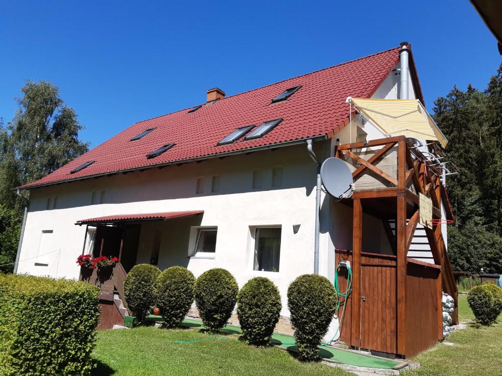 SokołowskoApartament Zielony Zakątek的白色的房子,有红色的屋顶和灌木丛