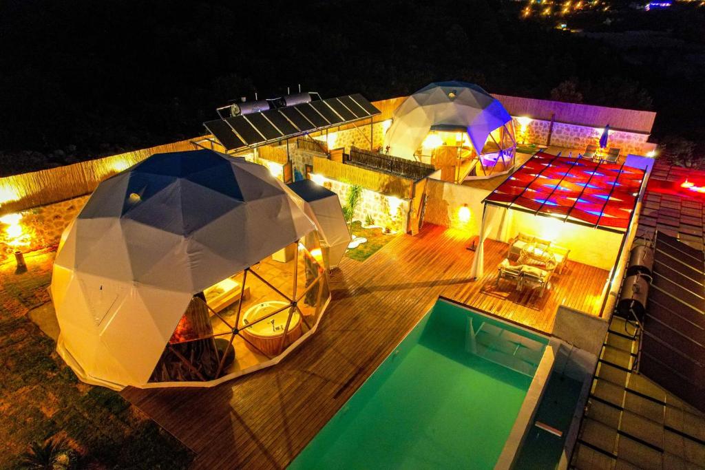 卡斯Kalkan Dome Suites & Deluxe-Glamping Holiday in Kalkan的享有房子顶部的景色,晚上有游泳池