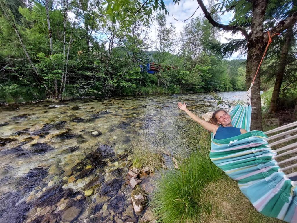 佐尔尼耶戈迪The RiverSide Chill Hostel的躺在河边吊床上的女人