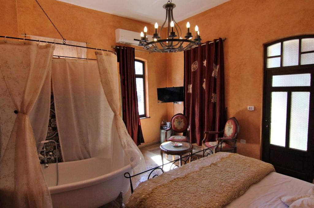 海法艾特里耶豪华酒店的一间带浴缸、床和吊灯的卧室
