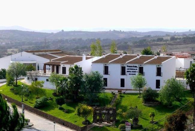 El GranadoPOSADA LOS PEDREGALES的一座白色的大建筑,有绿色的院子