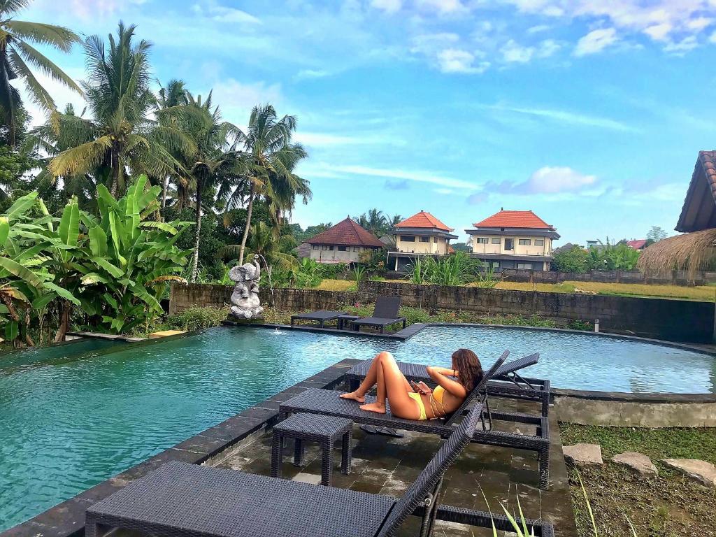 乌布Ubud Rice Field House的躺在游泳池旁长凳上的女人