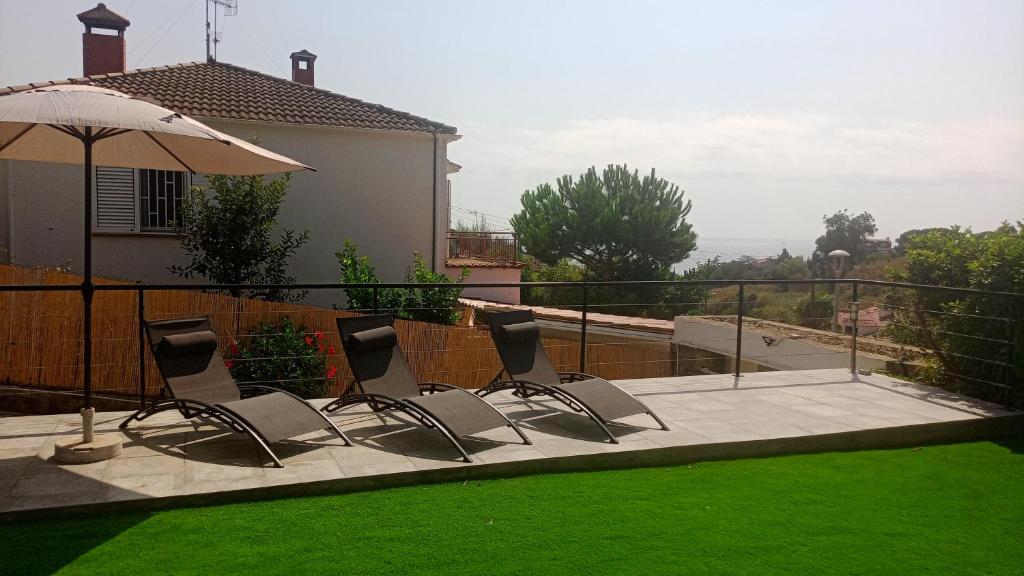 滨海阿雷尼斯Holidays en Arenys de Mar y Montaña的一组椅子坐在带遮阳伞的庭院