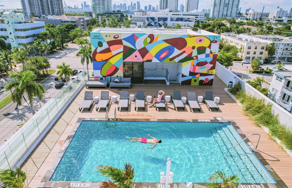 迈阿密海滩Urbanica Fifth的在建筑物顶部的游泳池游泳的人