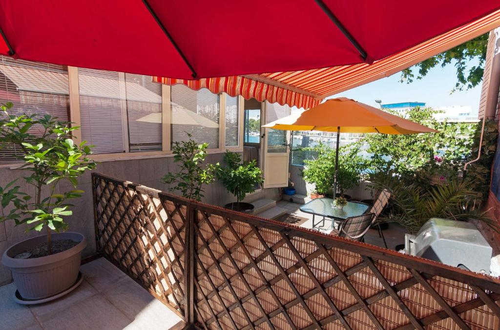 扎达尔Sobe Pegla的阳台配有红色雨伞和桌子