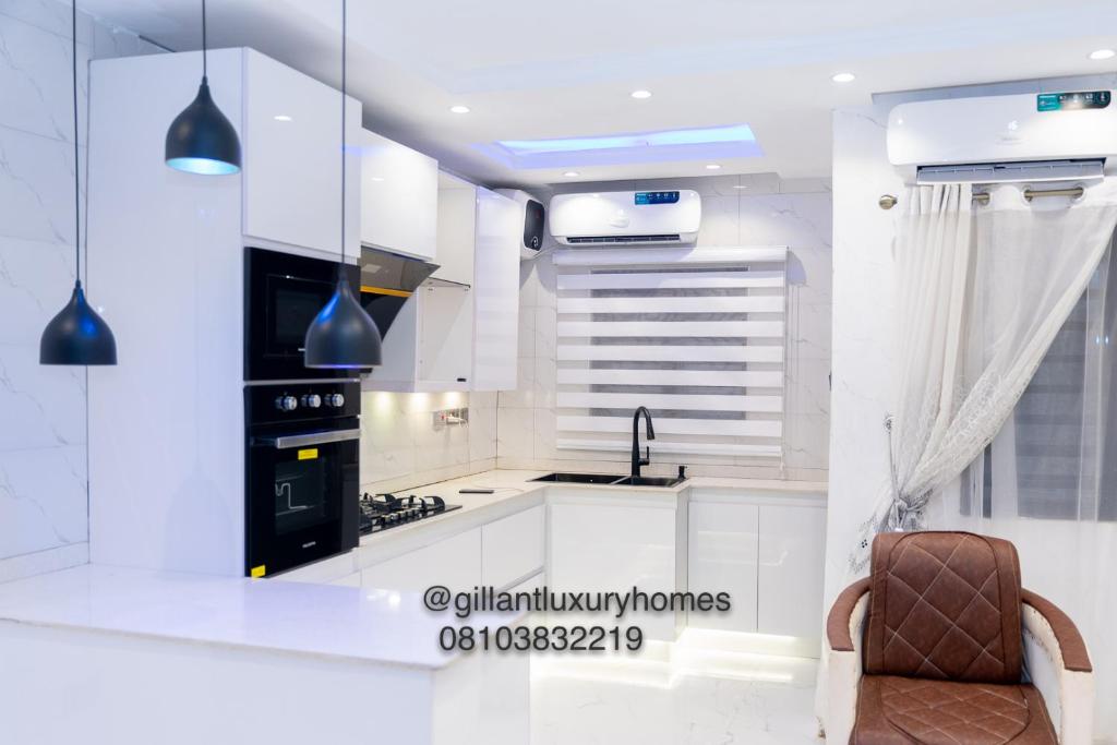 贝宁城Gillant Luxury Homes的厨房配有白色橱柜、水槽和椅子