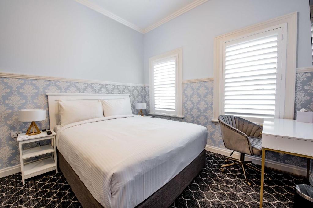 班克斯镇Bankstown Hotel的卧室配有一张床、一张书桌和窗户。