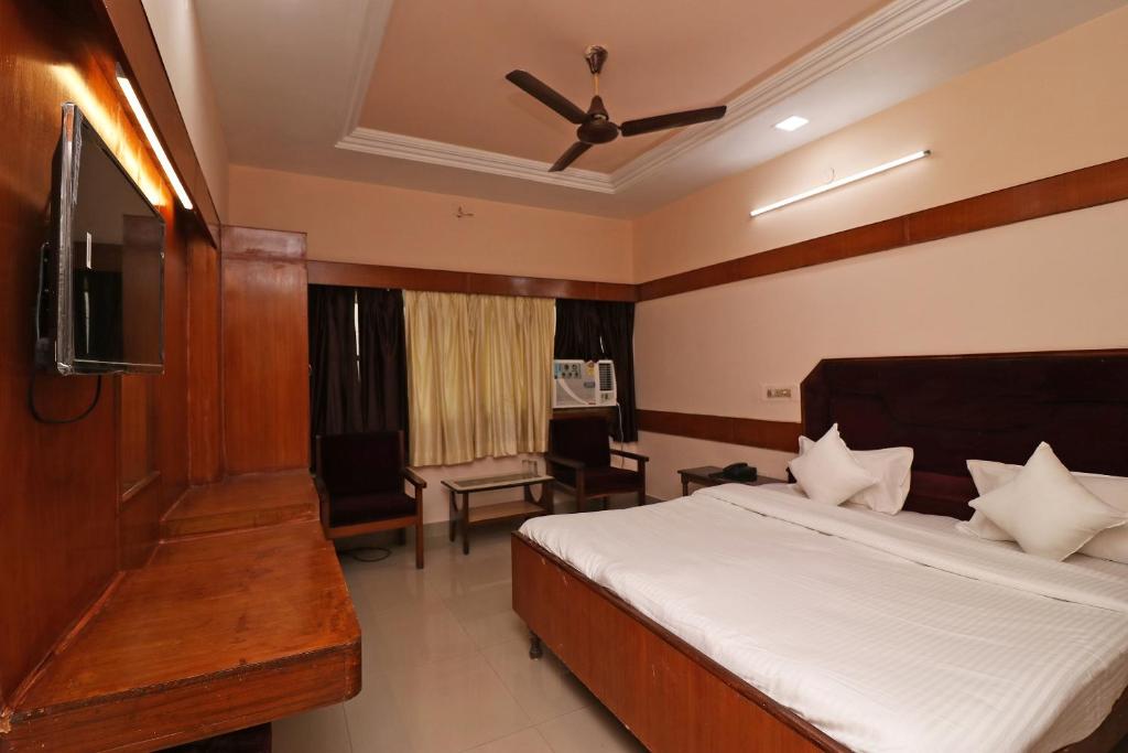 比拉斯布尔Hotel Natraj的一间卧室配有一张带吊扇的床和一台电视。
