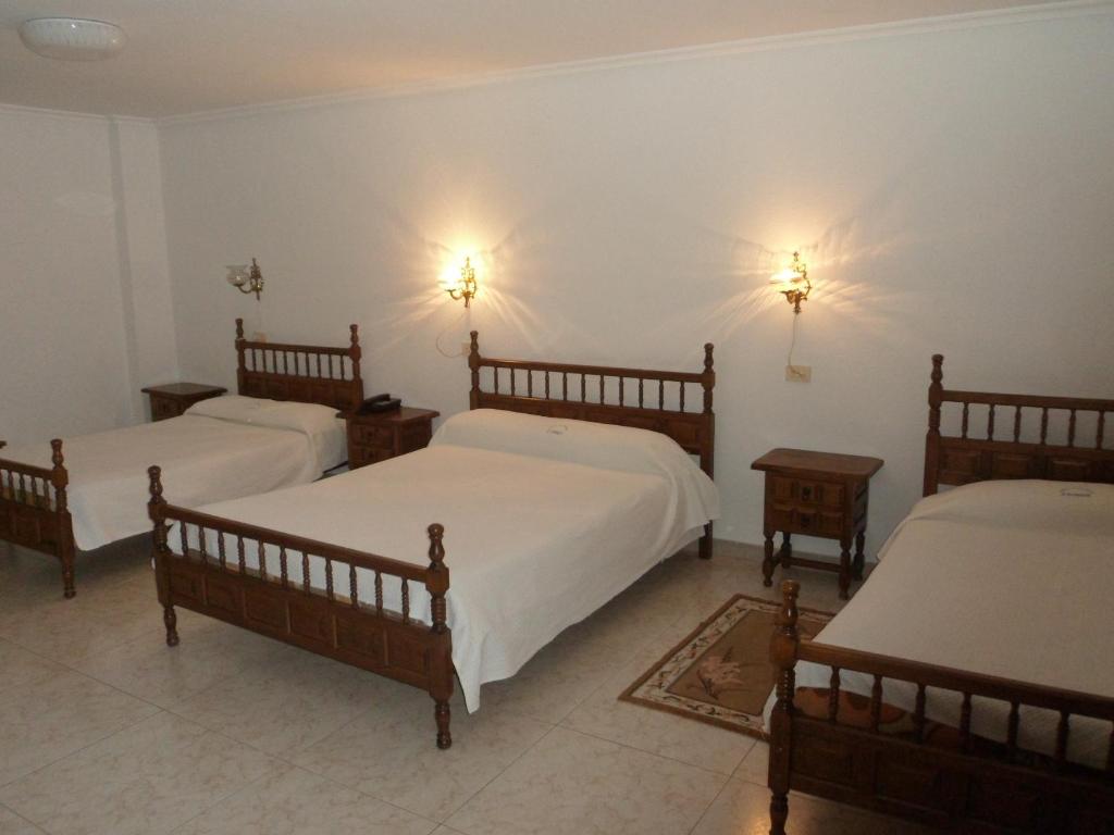 Taboadela孔德酒店的一间房间,设有三张床和两盏墙上的灯
