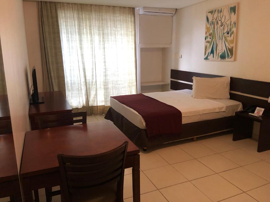 萨尔瓦多Studio 01 Modelo Flat的酒店客房配有一张床铺、一张桌子和一张书桌。