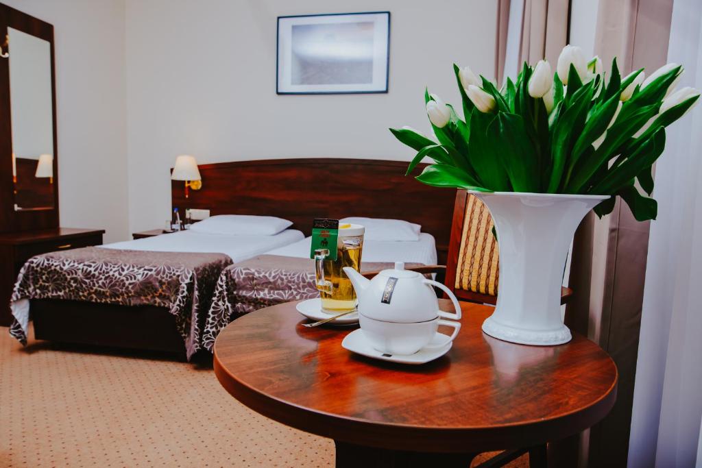波兹南科瑞尔酒店的一间酒店客房,配有一张带花瓶的桌子