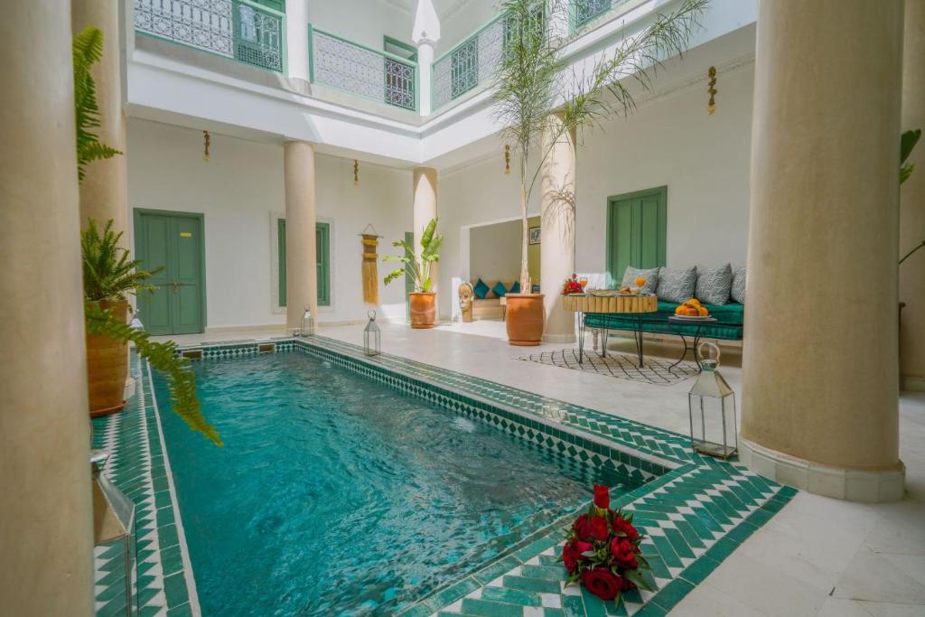马拉喀什Riad Trésor Marrakech的一座大型游泳池,位于带房子的房间里