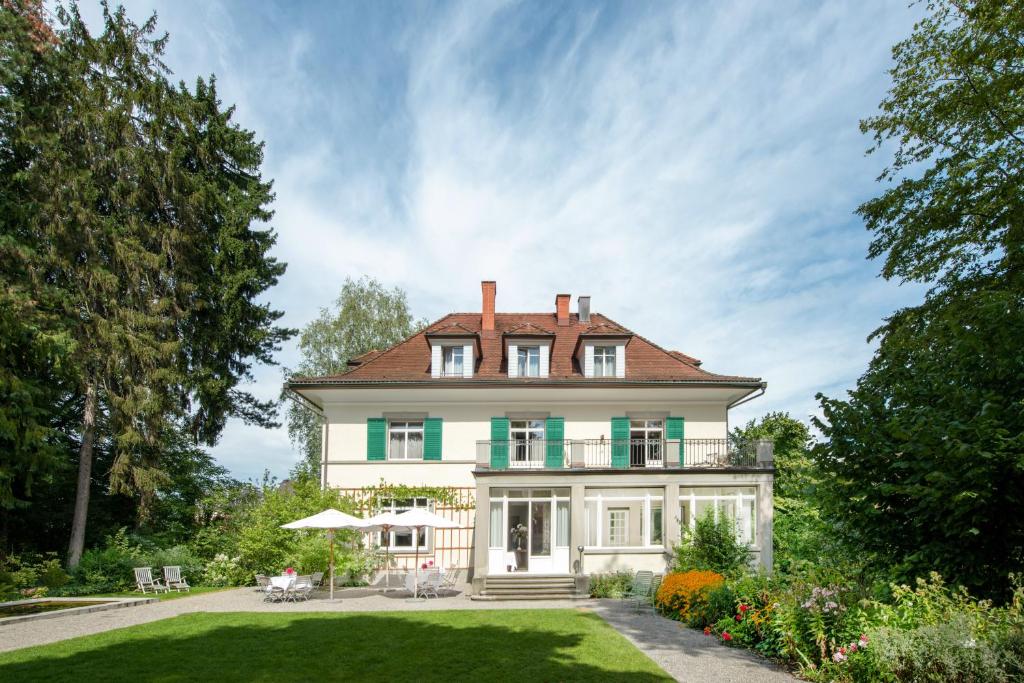 苏黎世Signau House & Garden Boutique Hotel Zürich的一座带绿色庭院的大型白色房屋