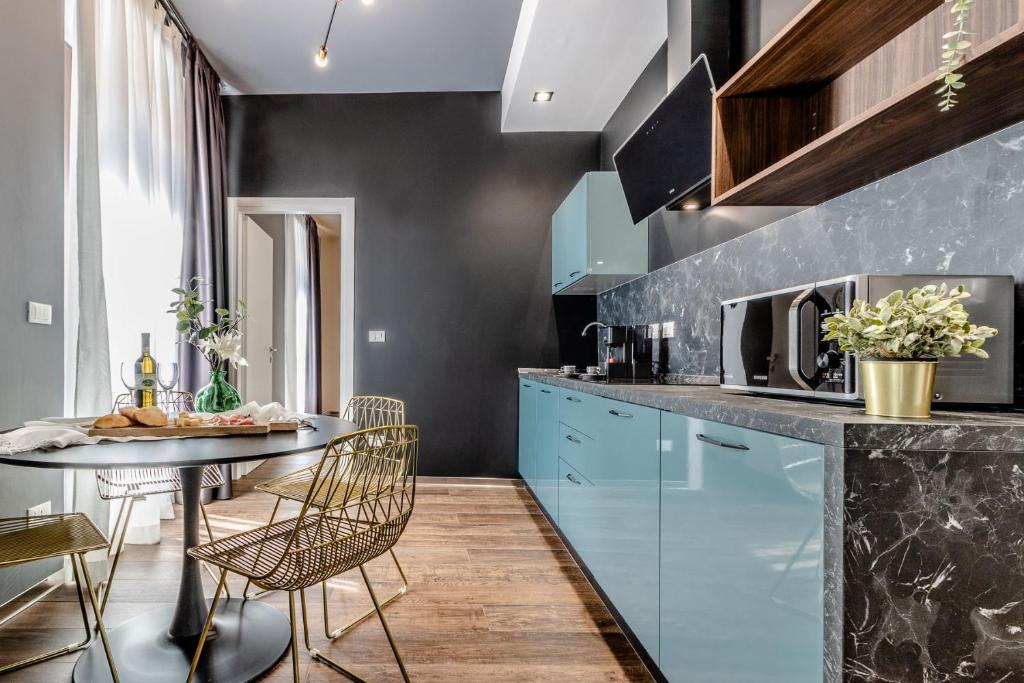 博洛尼亚Ugo Bassi Apartments的厨房配有蓝色橱柜和桌椅