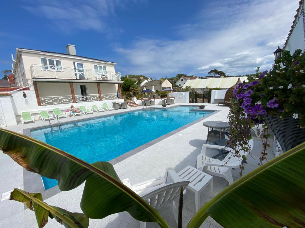 St Pierre du BoisBeau Vallon Holiday Apartments的房屋旁的游泳池,带白色椅子