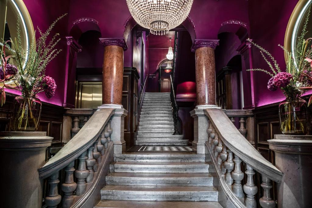 维也纳Hotel Josefine的紫色建筑中带有吊灯的螺旋楼梯