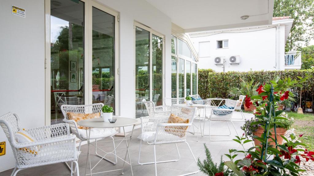 里乔内BeYou Hotel Villa Rosa的庭院配有白色的椅子和桌子