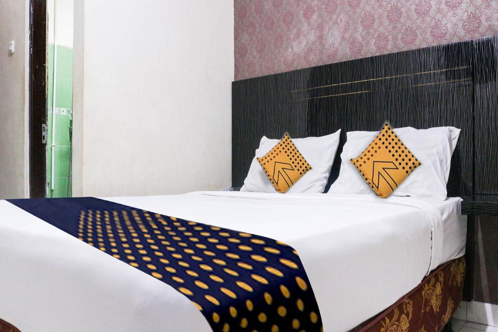 古邦SPOT ON 3605 Clarichie Guest House的一间卧室配有白色的床和黄色及蓝色枕头