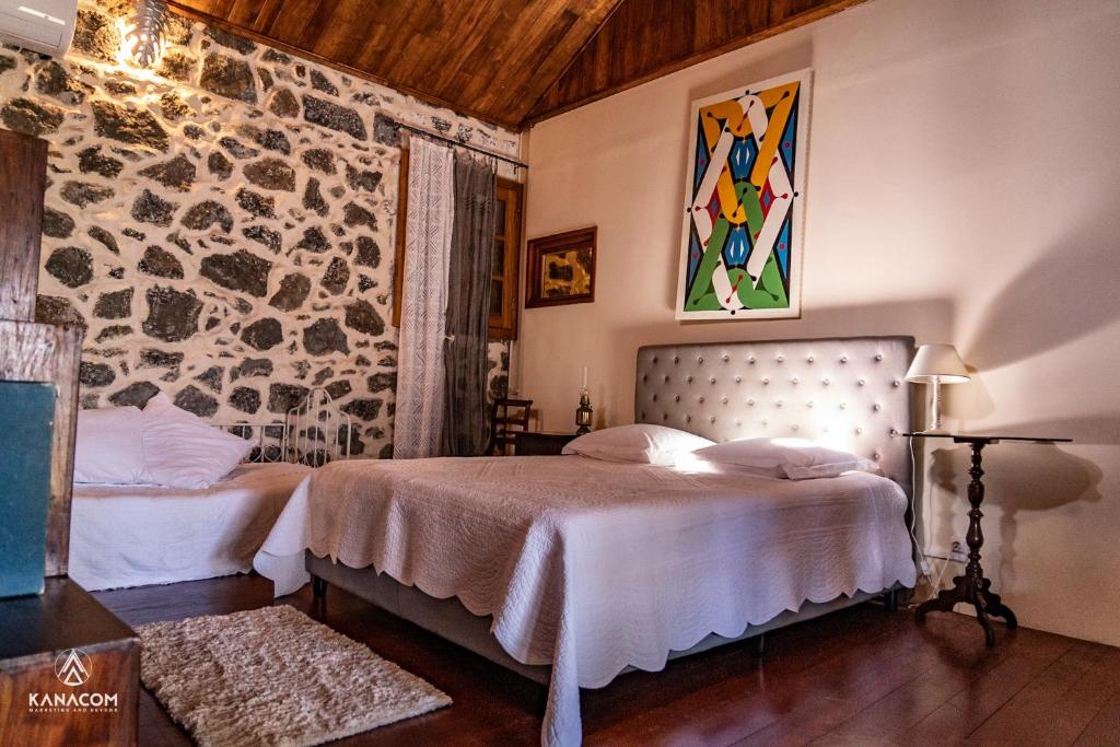圣若瑟Les Grands Monts的一间卧室设有两张床和石墙