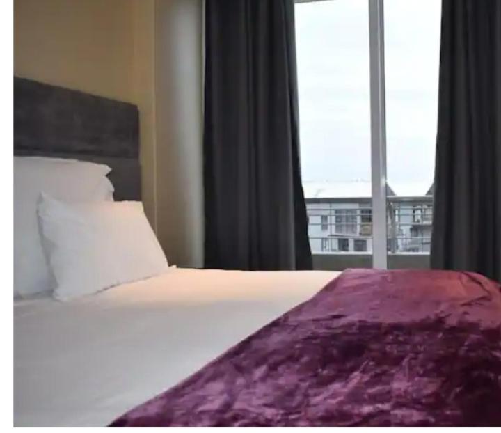 德班Three and two bedroom at The Sails的一张带紫色毯子和窗户的床
