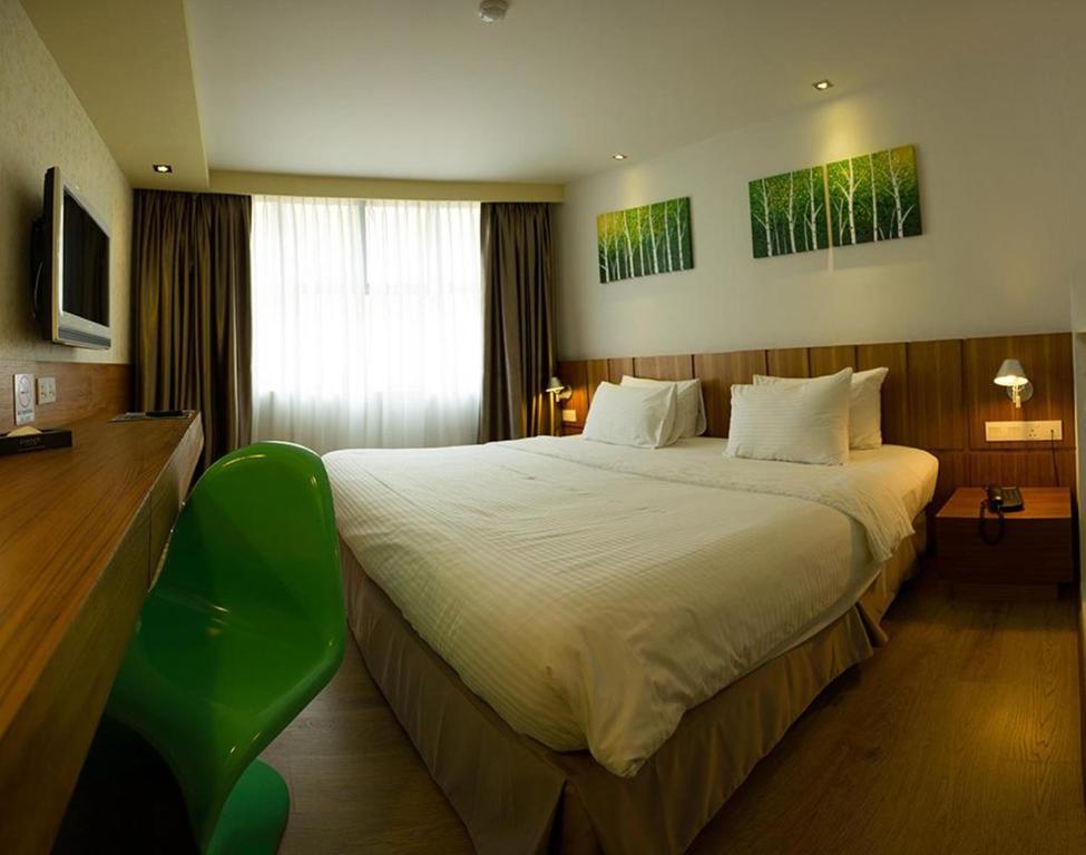 怡保法国酒店的酒店客房设有一张大床和一张绿色椅子。