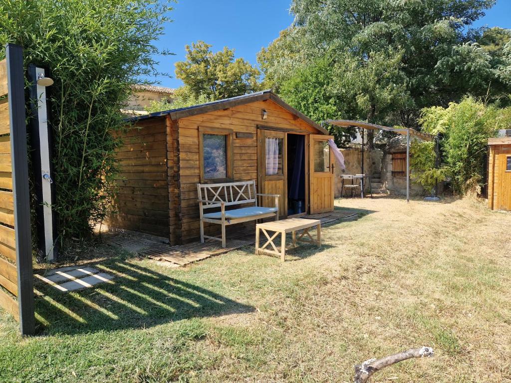 卡代纳Locations insolites "vie en plein air" cabane et tipi Bastide Bellugue maison d'hôtes reseau Bienvenue à la ferme à 3 mn de lourmarin的庭院内带长凳的小木屋