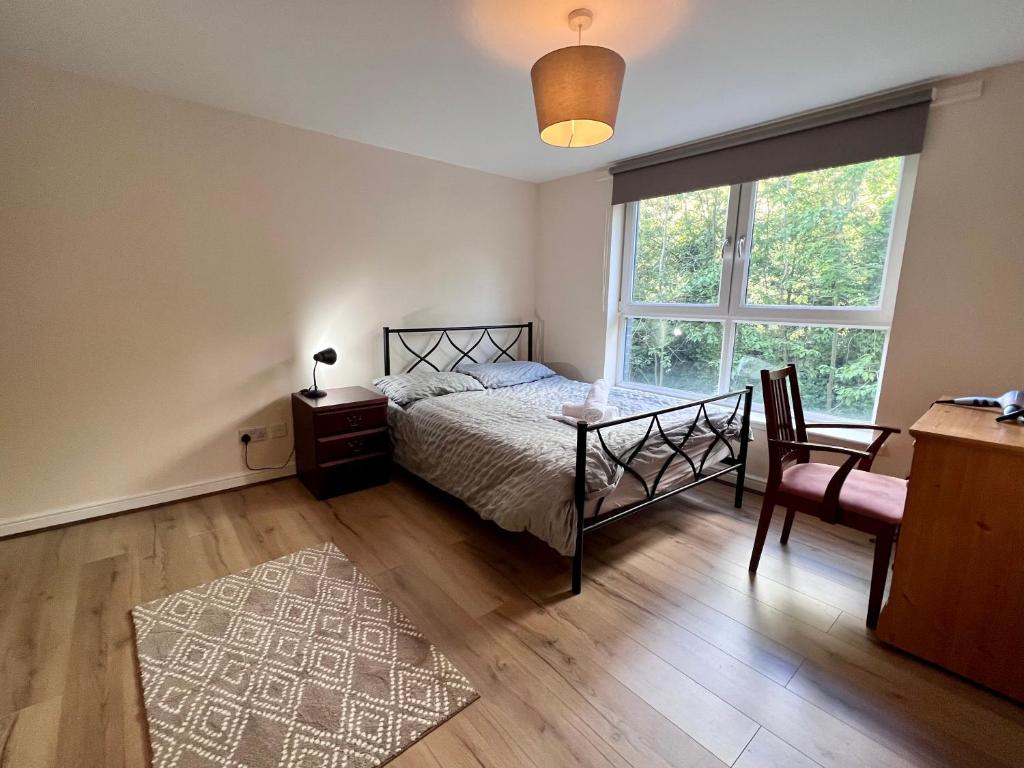 格拉斯哥Lovely 2-Bed Serviced apartment with free parking的一间卧室配有一张床、一张桌子和一个窗户。
