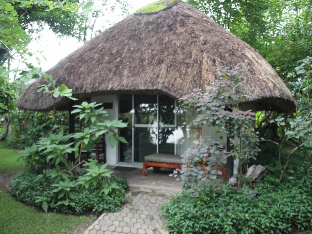 卡蒂马穆利洛Caprivi River Lodge的茅草屋顶的小房子,里面设有长凳