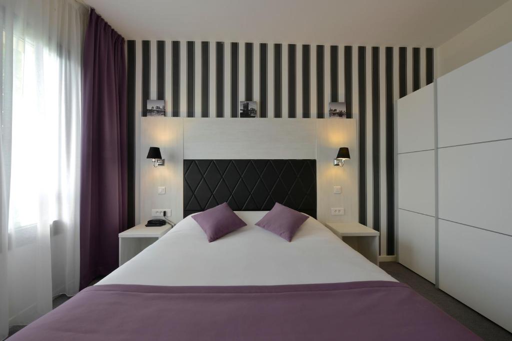 图瓦里伊特莱尔旅馆的卧室配有一张带紫色枕头的大型白色床。