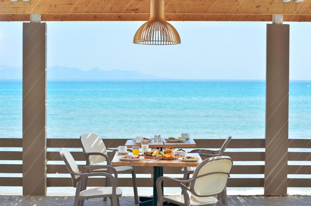 阿利卡纳斯Alykanas Beach Grand Hotel by Zante Plaza的一张桌子和椅子,背景是大海