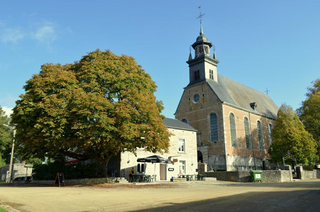 Foy-Notre-Dame乐维尤克斯马罗尼埃住宿加早餐旅馆的教堂前方有一座塔楼,前面有棵树