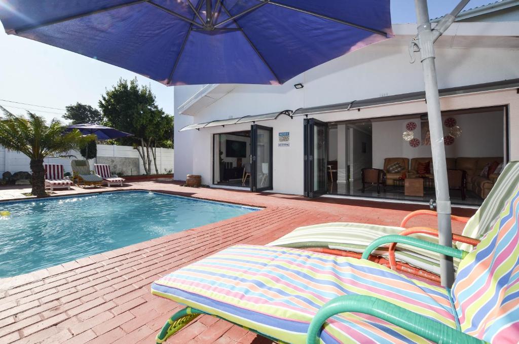 开普敦Casa Milner Guest House的一个带两把草坪椅和遮阳伞的游泳池