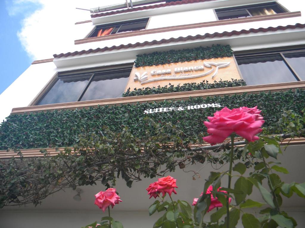 洛佩斯港Casa Blanca Puerto López的前面有标志和鲜花的建筑