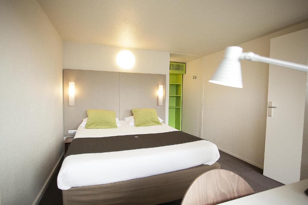 迪南Brit Hôtel Dinan - Taden的一间卧室配有一张带绿色枕头的大床