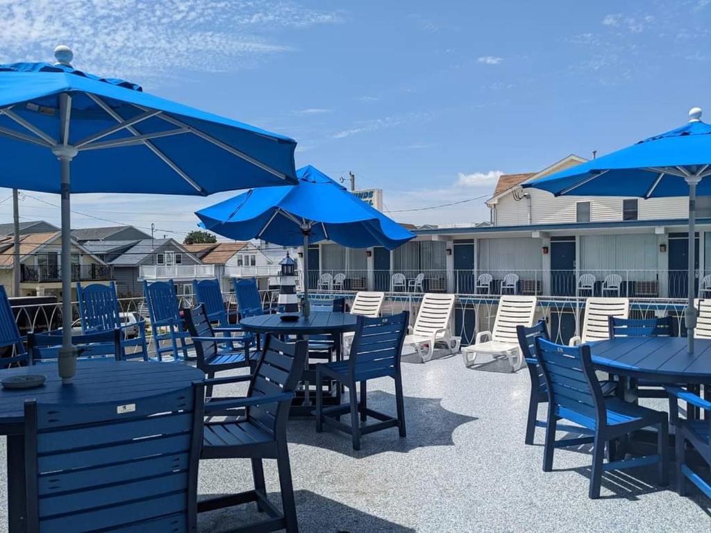 怀尔德伍德Tide Winds Motel的露台配有蓝色桌椅和蓝色遮阳伞