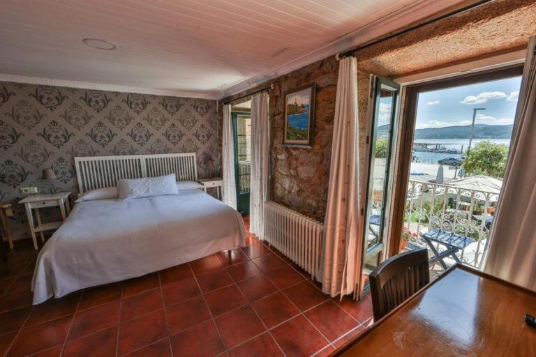卡马里尼亚斯Hotel Puerto Arnela的一间卧室设有一张床和一个大窗户