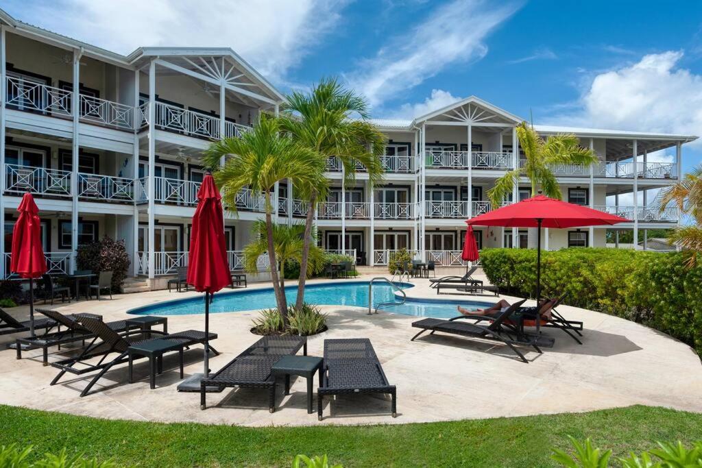 圣詹姆斯Private Condo on the West Coast of Barbados的一个带游泳池、椅子和遮阳伞的度假村