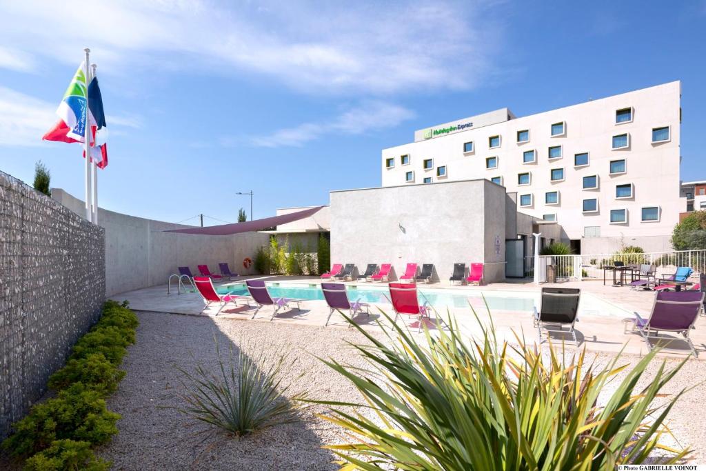 蒙彼利埃蒙彼利埃奥德修姆智选假日酒店的一座带游泳池、椅子和旗帜的酒店