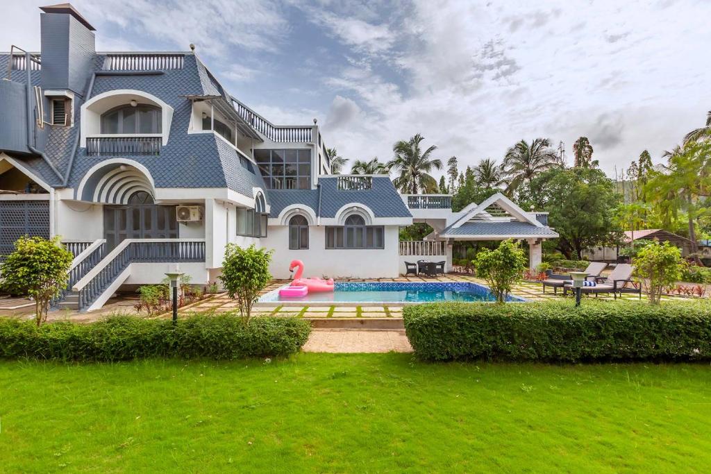 孟买Grey Mosaics by StayVista - Mountain-view villa in Vasai with Pool, Spacious lawn & Terrace的一座大房子,前面设有一个游泳池