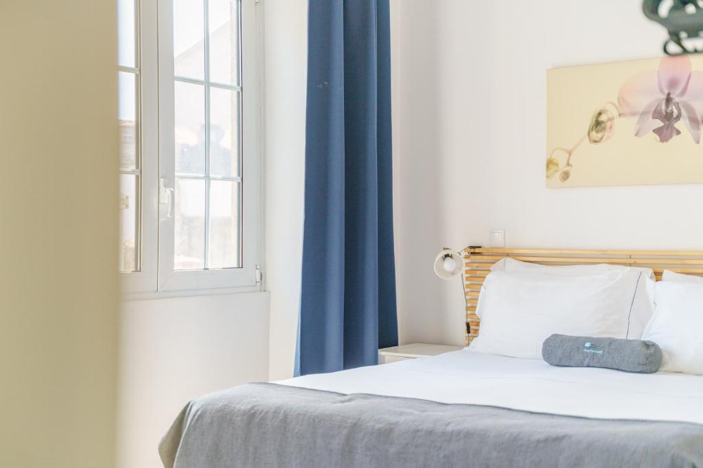 波尔图Feel Porto Historical Apartments的一间卧室配有一张带蓝色窗帘的床和窗户