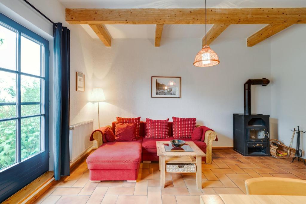 朗克维茨4-Raum Apartment bis 6 Pers 21的客厅配有红色沙发和燃木炉。