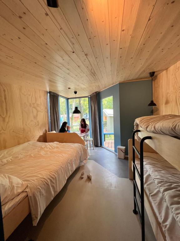 阿姆斯特丹Camping Vliegenbos的一间卧室设有两张床,一位女士坐在椅子上