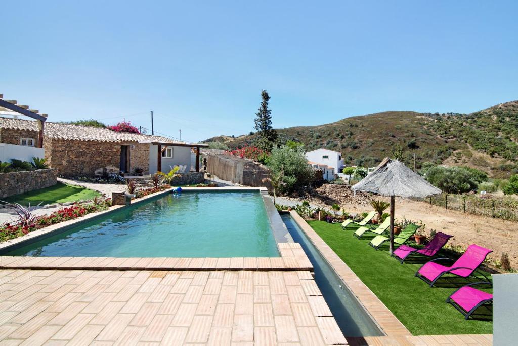 塔维拉Quinta do Silêncio T4的一个带草坪椅和遮阳伞的游泳池