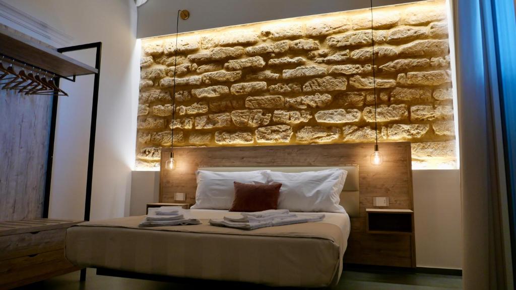 阿格里真托Oneira Rooms的卧室配有石墙,位于床上方