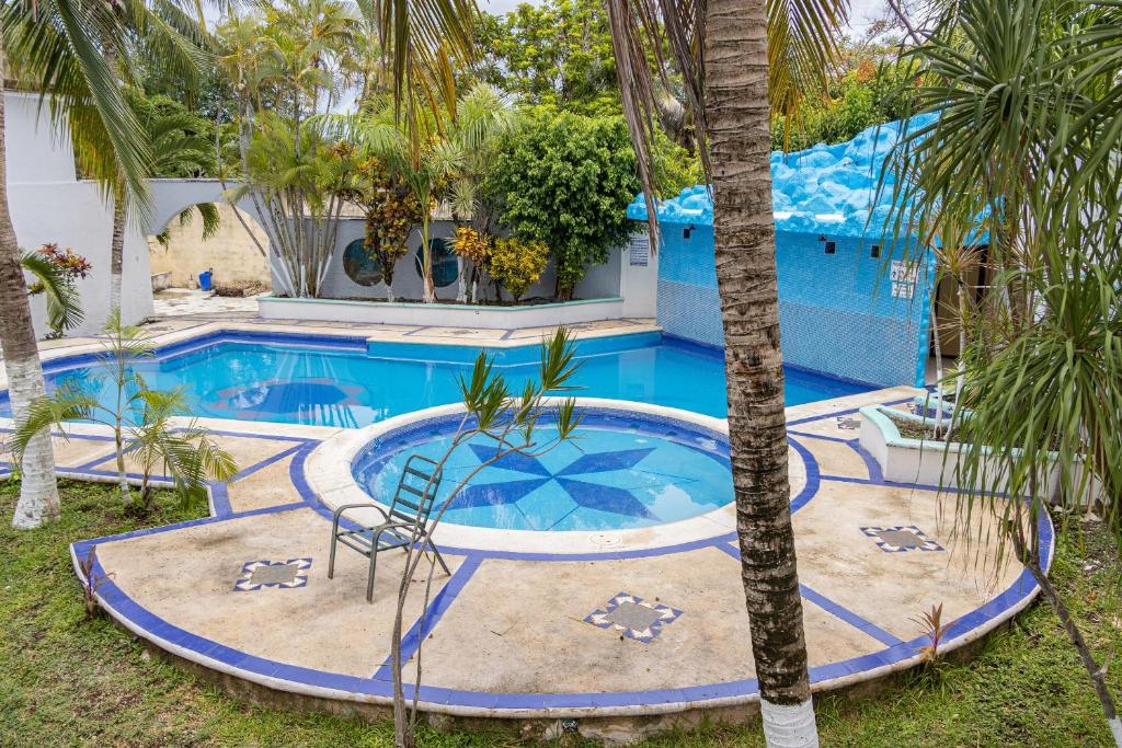 切图马尔OYO Hotel Marías,Aeropuerto Internacional de Chetumal的一座房子前面的游泳池,上面有棕榈树